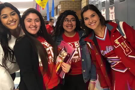 Vier Schülerinnen der Trinity Catholic Jr/Sr High School posieren gemeinsam lachend im Schulflur vor Schließfächern.