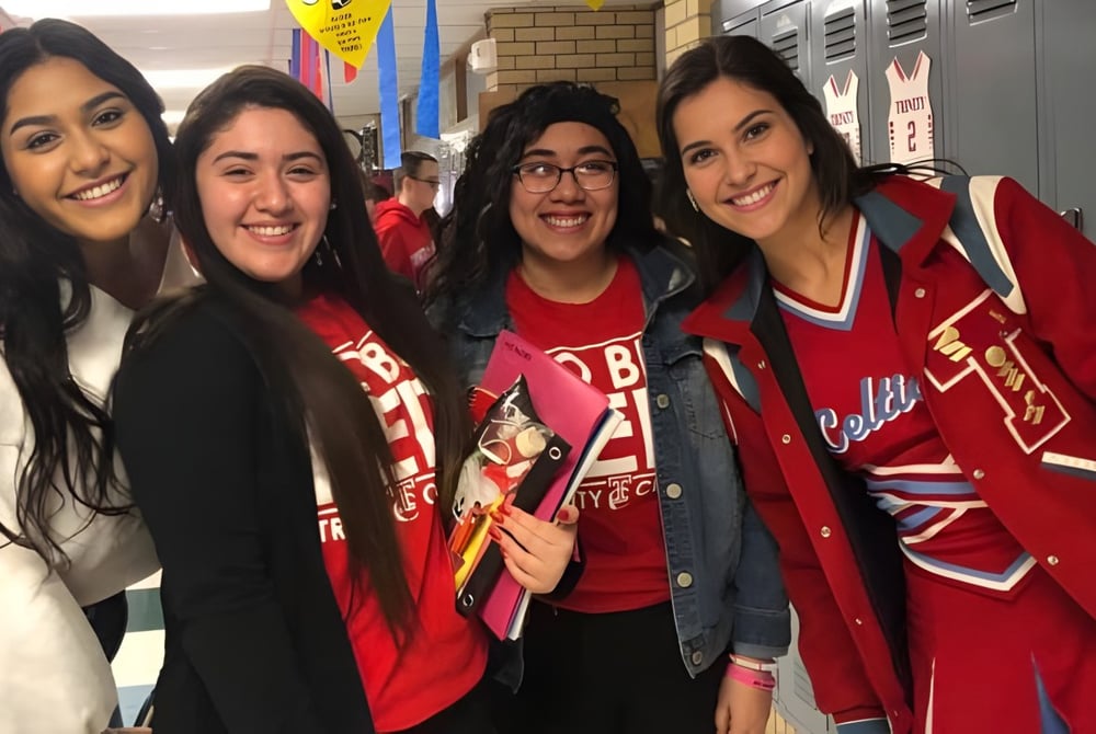 Vier Schülerinnen der Trinity Catholic Jr/Sr High School posieren gemeinsam lachend im Schulflur vor Schließfächern.