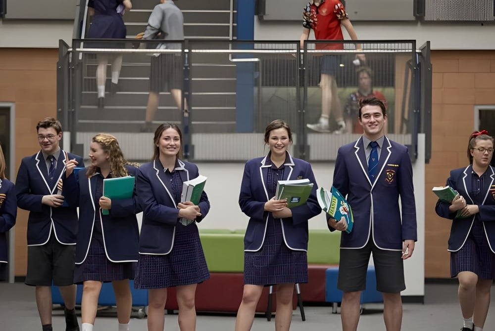 Eine Gruppe Schüler in Schuluniformen steht im Flur auf dem Campus des Trinity College.