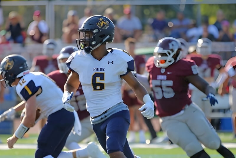 Ein Footballspieler der Trinity-Pawling School steht auf dem Spielfeld neben anderen Spielern in verschiedenen Trikots.