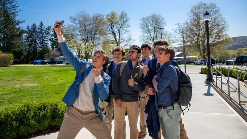 Eine Gruppe Schüler steht an einem sonnigen Tag auf dem Außengelände der Trinity-Pawling School mit Wiese und Bäumen im Hintergrund.