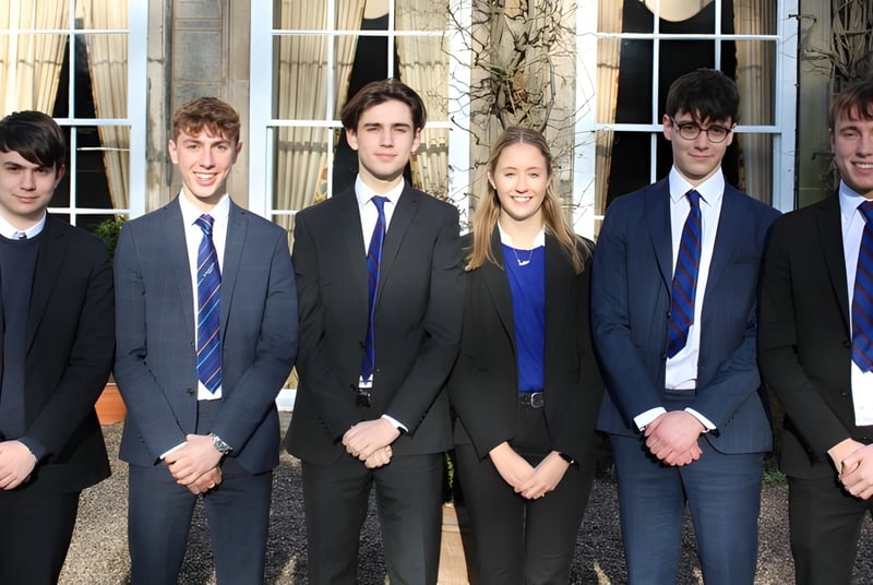 Eine Gruppe Jugendlicher steht vor einem Gebäude auf dem Campus der Trinity School.