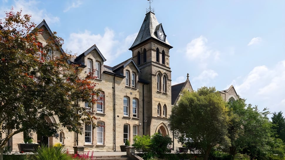 Das gotische Hauptgebäude der Truro School wird von Bäumen umgeben und steht in einer grünen Parkanlage.