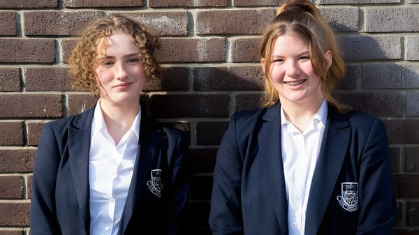 Zwei Schülerinnen der Truro School stehen vor einer Backsteinmauer.