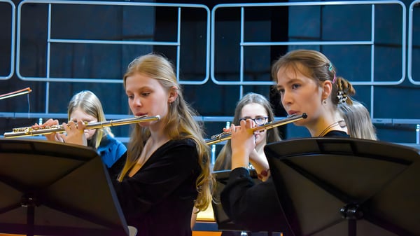 Zwei Schülerinnen der Tudor Hall School spielen Flöte auf einer Bühne mit dunklem Hintergrund.