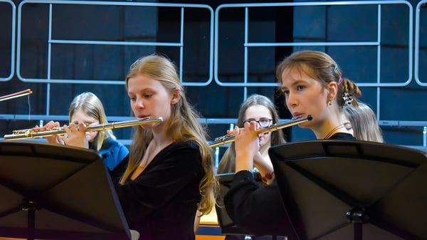 Zwei Schülerinnen der Tudor Hall School spielen Flöte auf der Bühne vor dunklem Hintergrund mit Beleuchtung.