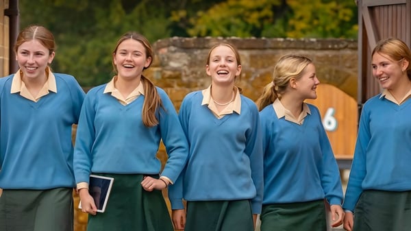 Fünf Schülerinnen der Tudor Hall School stehen zusammen vor herbstlichem Laub und lachen.