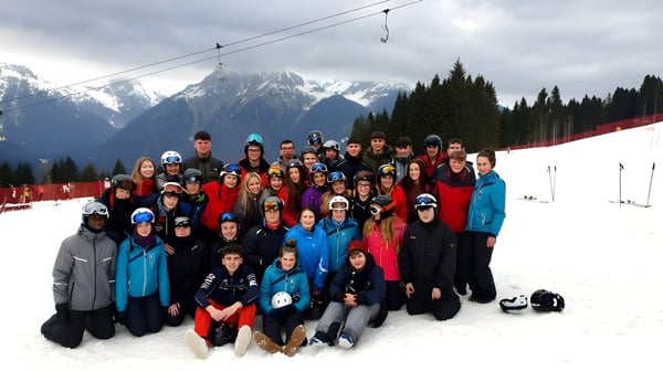 Eine Gruppe von Schülerinnen und Schülern des Tullamore College steht in bunter Winterkleidung in einer verschneiten Berglandschaft.