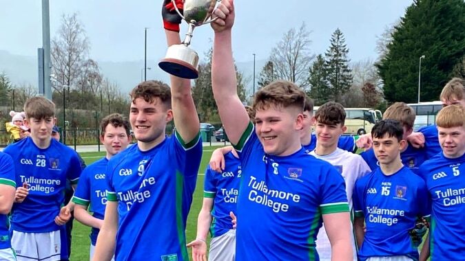 Eine Gruppe männlicher Schüler vom Tullamore College feiert ihren Sieg auf dem Sportplatz vor Bäumen und Gebäuden.