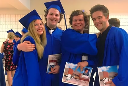 Eine Gruppe von vier Schülern der Twin Lakes Secondary School in blauen Abschlussroben posiert gemeinsam.