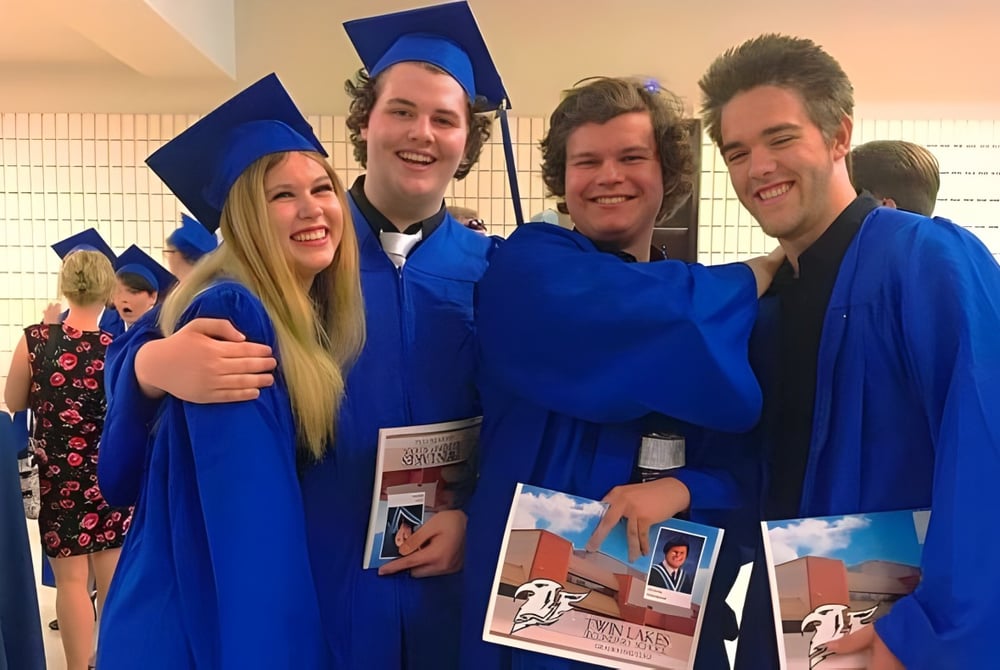 Eine Gruppe von vier Schülern der Twin Lakes Secondary School in blauen Abschlussroben posiert gemeinsam.