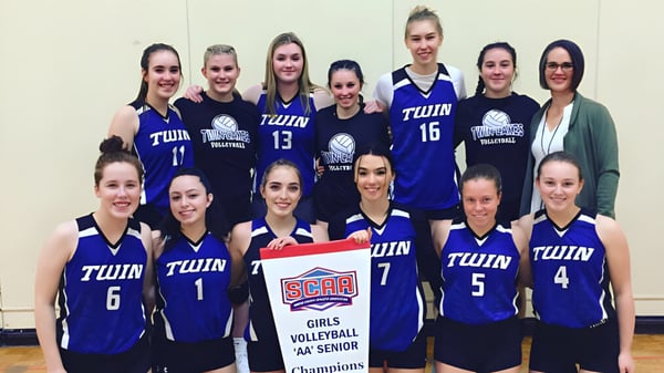 Eine Gruppe weiblicher Volleyballspielerinnen der Twin Lakes Secondary School posiert gemeinsam in der Sporthalle.