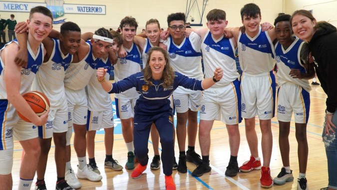 Eine Gruppe von Schülern des Tyndall College feiert gemeinsam im Sporthallen-Basketballspiel ihren Erfolg.