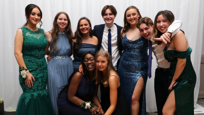 Eine Gruppe von Schülerinnen und Schülern des Tyndall College posiert gemeinsam bei einer formellen Veranstaltung vor einem weißen Hintergrund.