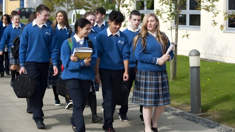Eine Gruppe Schülerinnen und Schüler des Tyndall College geht gemeinsam auf einem Weg, umgeben von Bäumen und Gebäuden.