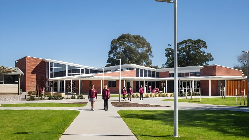 Das moderne Gebäude der Underdale High School ist von einer Wiese und Bäumen umgeben, vor dem Haupteingang laufen mehrere Personen auf einem Weg.