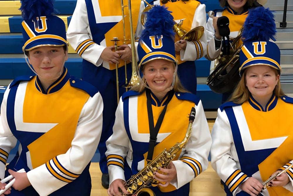 Eine Gruppe Cheerleader der Union High School steht in einheitlichen gelb-blauen Uniformen in der Sporthalle.