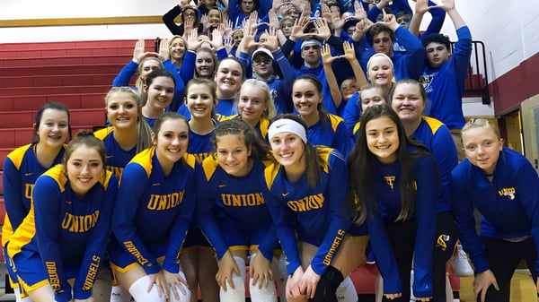 Eine Gruppe Schülerinnen der Union High School steht in blauen und gelben Uniformen in einer Sporthalle zusammen.