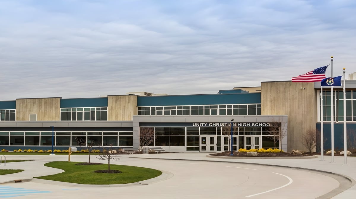 Das moderne Schulgebäude der Unity Christian High School mit amerikanischer Flagge und angelegten Wegen ist zu sehen.