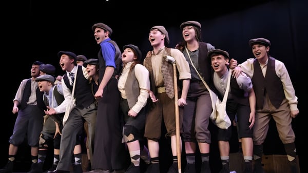 Schüler der Unity Christian High School in Theaterkostümen posieren auf einer Bühne mit dramatischer Beleuchtung.