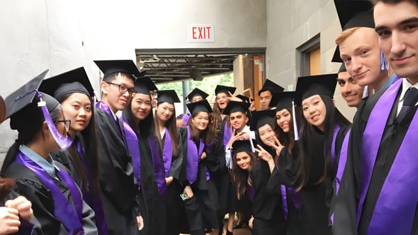 Absolventinnen und Absolventen der University Hill Secondary School stehen in violetten Talaren in einem Flur zusammen.