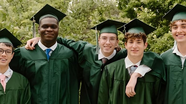Eine Gruppe Absolventen steht in grünen Talaren im Freien auf dem Campus der University Lake School.