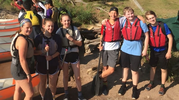 Eine Gruppe Schüler der University Lake School steht in Wanderkleidung auf einem Weg inmitten grüner Natur.