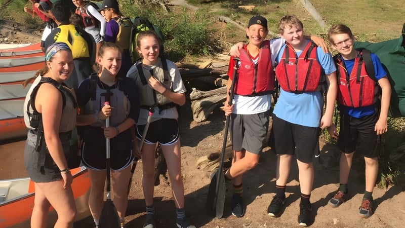 Eine Gruppe Schüler der University Lake School steht in Wanderkleidung auf einem Weg inmitten grüner Natur.