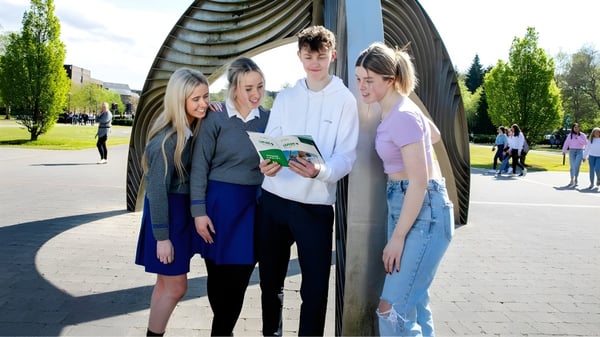 Eine Gruppe von Schülerinnen und Schülern steht im Freien vor einer markanten architektonischen Struktur auf dem Campus der University of Limerick.
