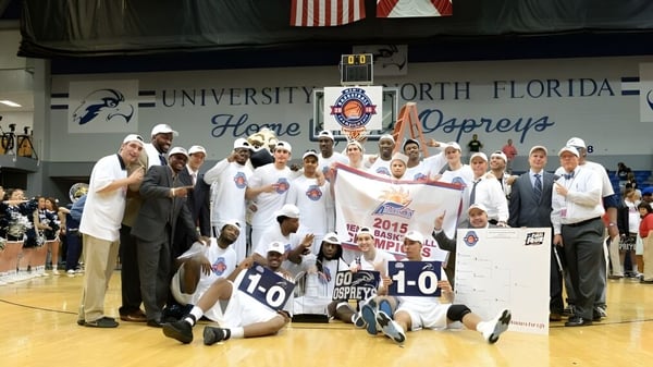 Schüler der University of North Florida feiern auf dem Basketballfeld mit einem Meisterschaftsbanner ihren Sieg.