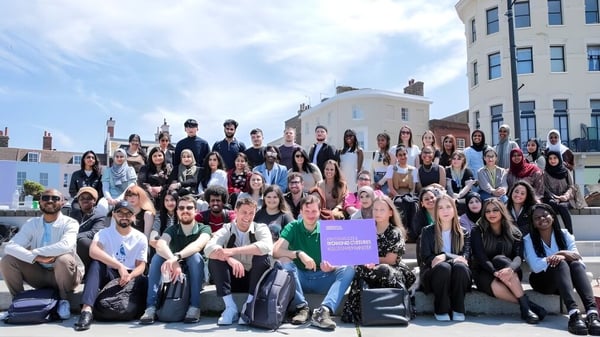 Eine Gruppe von Studierenden versammelt sich vor einem Gebäude auf dem Campus der University of Westminster unter blauem Himmel.
