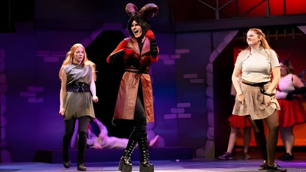 Schüler in bunten Kostümen führen auf der Bühne der University of Wisconsin-Superior vor farbigem Hintergrund eine Aufführung auf.