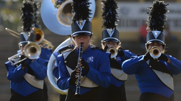 Die Marching Band des Upper Canada College tritt auf einer Bühne vor einem Stadion auf.