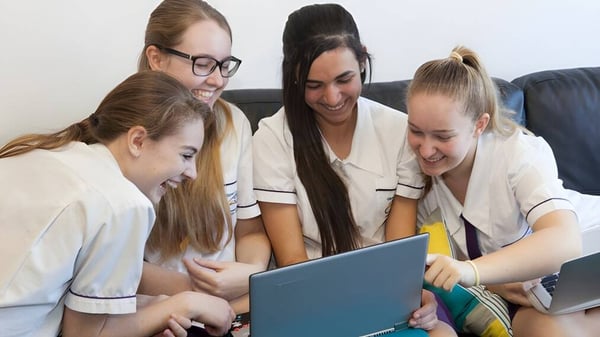 Eine Gruppe Schülerinnen des Upper Coomera State College arbeitet gemeinsam an einem Laptop.
