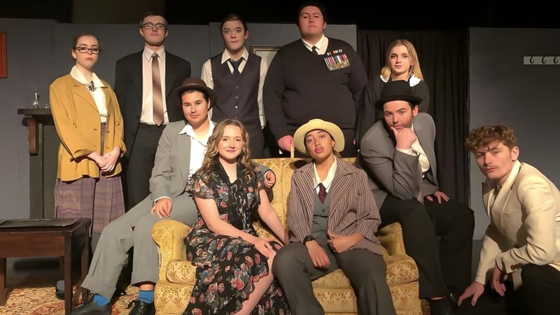 Eine Gruppe Schüler des Upper Hutt College steht in formeller Kleidung auf der Bühne mit Bühnenrequisiten im Hintergrund.