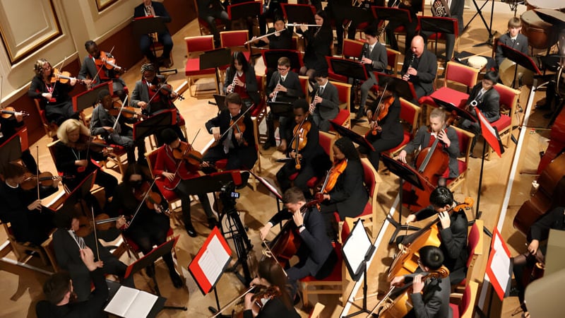 Eine große Gruppe von Absolventen der Uppingham School versammelt sich in einem prächtigen Saal zur Abschlussfeier.