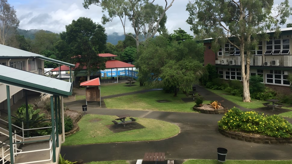 Der grüne Campus mit einem geschwungenen Weg und Gebäuden mit roten Dächern der Urangan State High School.