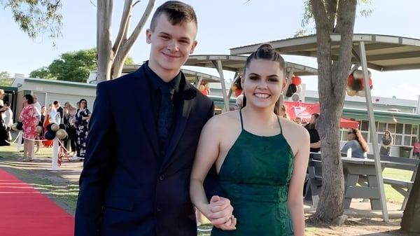 Ein junges Paar steht zusammen auf dem roten Teppich auf dem Gelände der Urangan State High School.