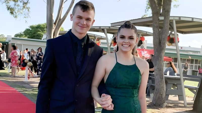 Ein junges Paar steht zusammen auf dem roten Teppich auf dem Gelände der Urangan State High School.