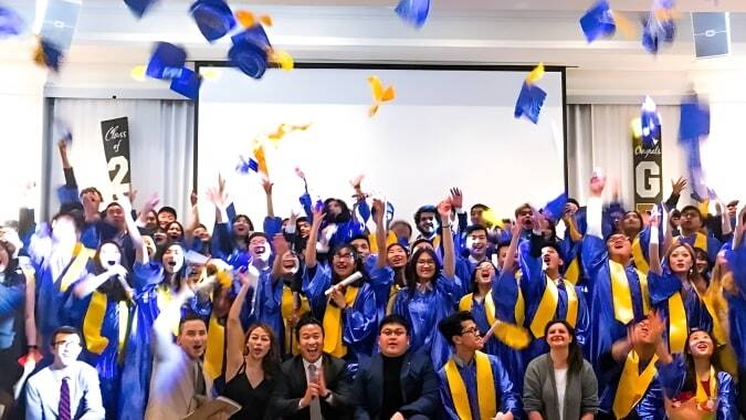 Schüler der Urban International High School feiern ihren Abschluss und werfen ihre Hüte in die Luft.