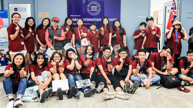 Eine Gruppe junger Schülerinnen in roten Shirts steht in einem Raum mit Postern auf dem Campus der Urban International High School.