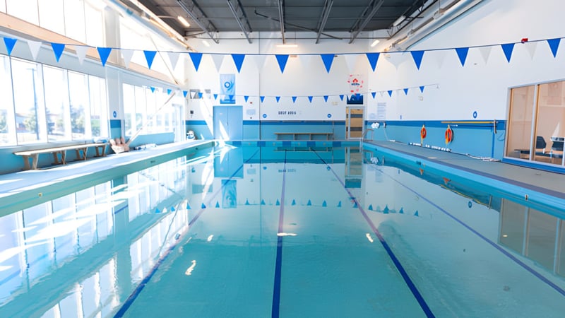 Das Hallenbad der Urban International High School mit blauen und weißen Fahnen an der Decke und großen Fenstern für natürliches Licht.