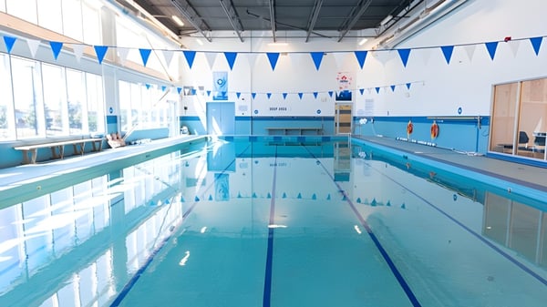 Das Hallenbad der Urban International High School zeigt eine blau-weiße Farbgestaltung und dekorative Fahnen an der Decke.