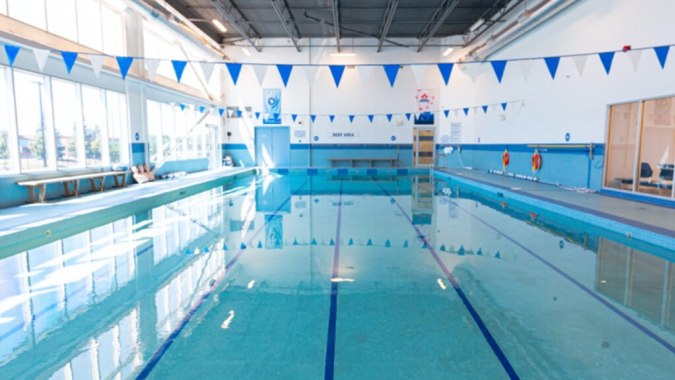 Die Schwimmhalle der Urban International High School zeigt ein Becken mit blauen und weißen Fahnen an der Decke.