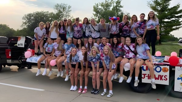 Eine Gruppe Schülerinnen des Urbandale Community School District posiert vor einem Fahrzeug im Freien bei klarem Himmel.