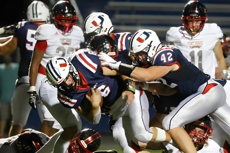 Schüler der Urbandale High School führen einen Football-Tackle auf dem Spielfeld aus.
