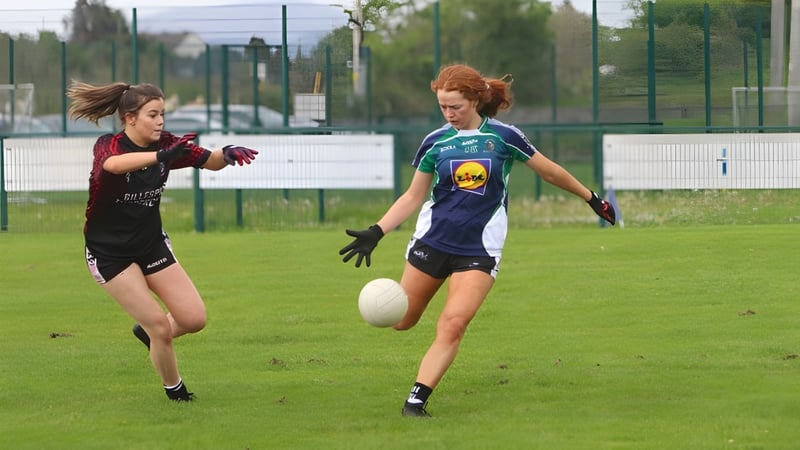 Zwei Schülerinnen des Ursuline College Sligo laufen in Sportkleidung auf einem Rasenplatz mit Sportanlage im Hintergrund.