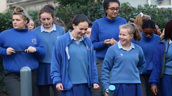 Eine Gruppe von Schülern der Ursuline Secondary School in Cork steht im Freien vor Bäumen und Gebäuden.
