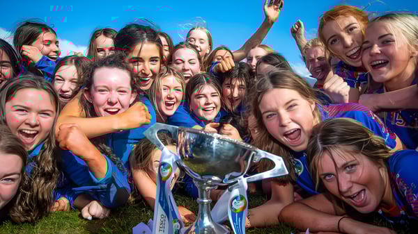 Eine Gruppe junger Schülerinnen der Ursuline Secondary School Thurles steht draußen zusammen und hält eine Trophäe in der Hand.