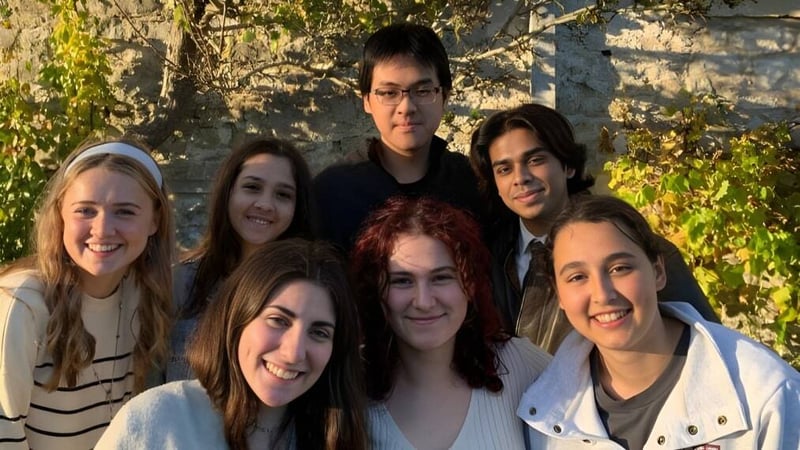 Eine Gruppe von Schülerinnen und Schülern posiert vor einer Steinmauer auf dem Gelände des UWC Atlantic College.